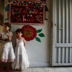 Dos chicas dan la bienvenida con una bandeja de dátiles a la entrada de su colegio en la ciudad de Duma, en Damasco.