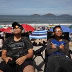 Unos niños usan gafas de sol para disfrutar del eclipse desde la playa en Mazatlán (México)