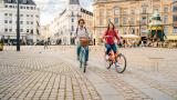 Dos turistas pasean en bicicleta por las calles de Copenhague.