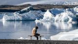 Una mujer descansando cerca de la orilla del lago Jökulsárlón, en Islandia
