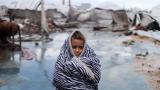 Una niña se protege del frío frente a la tienda de campaña de su familia, dañada por una tormenta, en un campamento de desplazados en Gaza ciudad, el 13 de enero de 2026.