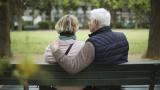 Una pareja de ancianos sentada en un banco público en un jardín público.