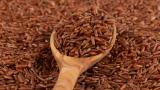 Red rice in a wooden spoon on red rice background