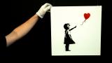 FILE PHOTO: A gallery technician adjusts Banksy's artwork "Balloon Girl" at Sotheby's auction house at Olympia in London, February 2, 2007.  REUTERS / Luke MacGregor