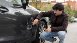 Un conductor mira un rasguño de su coche