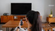 Una mujer encendiendo su televisión