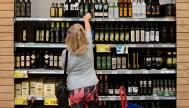 Una mujer coge una botella de aceite de oliva en un supermercado de Carrefour.