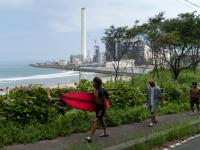 Un grupo de surfistas pasa por delante de la central nuclear de Fukushima.