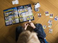 Un niño completando una colección de cromos de fútbol.