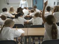 Imagen de una alumna levantando la mano en el colegio.