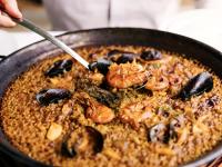 Una persona sirviendo una sartén de paella