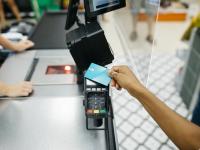 Primer plano de una mano pagando con tarjeta de crédito en un supermercado