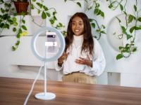 African woman making a video blog with smartphone and ring light at studio. Influencer recording a video for his social media channel.
