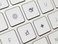 Un teclado en el que varias teclas han sido reemplazadas por los logos de OpenAI, DeepSeek, Grok y Gemini