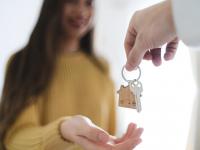 Una mujer recibiendo la llave de su nuevo hogar en un salón luminoso