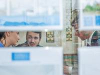 Imagen de una pareja conversando con un agente inmobiliario, vista desde el otro lado del escaparate.