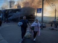 Varias personas caminan cerca de un edificio en llamas, al salir de un refugio tras los ataques nocturnos con misiles y drones rusos, el 24 de mayo de 2026, en Kiev.