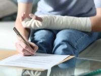 Una mujer con un brazo vendado firmando una baja