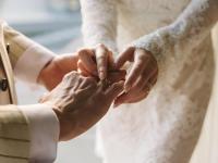 Una novia colocando el anillo en el dedo al novio en una boda