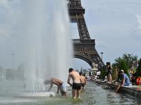 Parisinos se refrescan en las fuentes cerca de los Jardines del Trocadero, con la torre Eiffel al fondo en París.