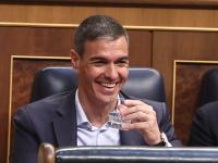 El presidente del Gobierno, Pedro Sánchez, riéndose en el Congreso, con un vaso de agua en la mano.