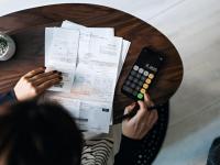 Una mujer organizando sus facturas y calculando cuánto tiene que pagar
