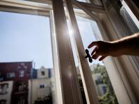 Una persona cerrando la ventana de casa para que no entre el calor