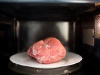 Un trozo de carne descongelándose en el microondas.