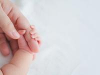 Una madre le sujeta la mano a un bebé recién nacido