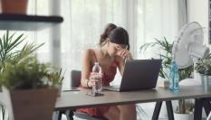 Imagen de archivo de una chica en una jornada de altas temperaturas, mientras mira su portátil.