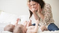 Una mujer jugando al cucú-tras con sus bebés.