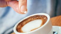 Una persona endulzando un café con aspartamo.