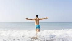 Un hombre en bañador entrando en el mar.