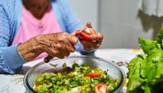 Una mujer corta varios tomates para preparar una ensalada.