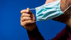 Imagen de archivo de un hombre retirándose la mascarilla.