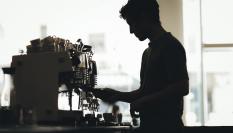 La silueta de un barista preparando café en una cafetería.