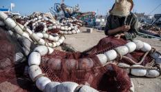 Un pescador cose las redes en el puerto de Essaouira, Marruecos.