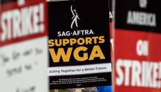 Fotografía de archivo fechada el 6 de junio de 2023 que muestra a un manifestante mientras sostiene un cartel que dice "el Sindicato de Actores de Cine-Federación Estadounidense de Artistas de Radio y Televisión (SAG-Aftra) apoya al Sindicato de Guionistas de Estados Unidos (WGA)", frente a los estudios Paramount en Los Ángeles, California (EE.UU).
