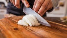 Imagen de archivo de una persona cortando cebolla.