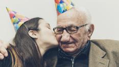 Imagen de archivo de un abuelo recibiendo un beso de su nieta.