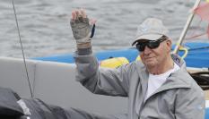 El rey emérito Juan Carlos I saluda desde la embarcación a su llegada este jueves al Real Club Náutico de Sanxenxo.