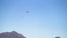 Un helicóptero sobrevuela la zona afectada por el fuego en Portbou (Girona) este sábado.