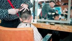 Foto de archivo de un peluquero cortándole el pelo a un niño