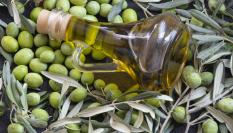 Imagen de archivo de una botella de aceite, sobre una cama de olivas.