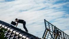 Imagen de archivo de un hombre instalando placas solares en el tejado de una vivienda.