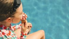 Una chica come un helado en una piscina en una imagen de archivo.