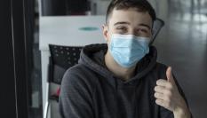 Imagen de archivo con un joven con mascarilla haciendo un gesto afirmativo con el pulgar.