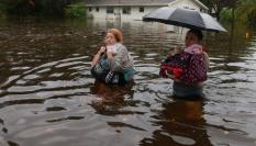 Dos mujeres, con el agua por la cintura, caminan por una ciudad de Floridad tras el paso del huracán Idalia.