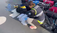 Una agente inspeccionando los fardos de cocaína intervenidos durante el registro al velero.