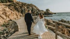 Dos personas recién casadas dan un paseo junto al mar en una imagen de archivo.